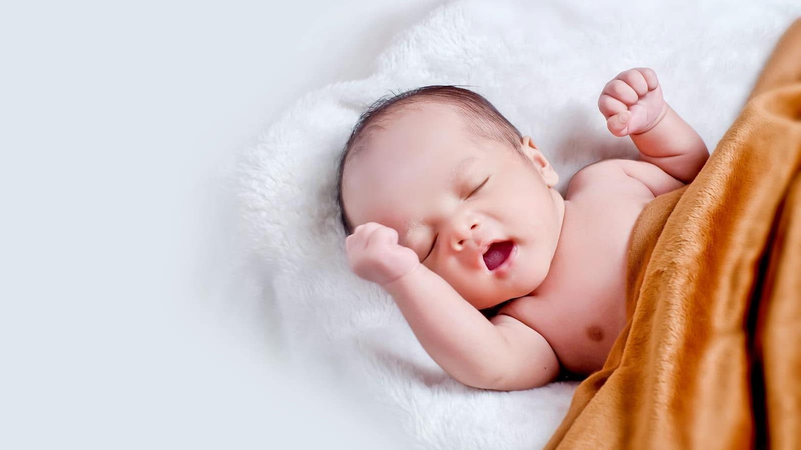 Baby Lying On White Fur With Brown Blanket